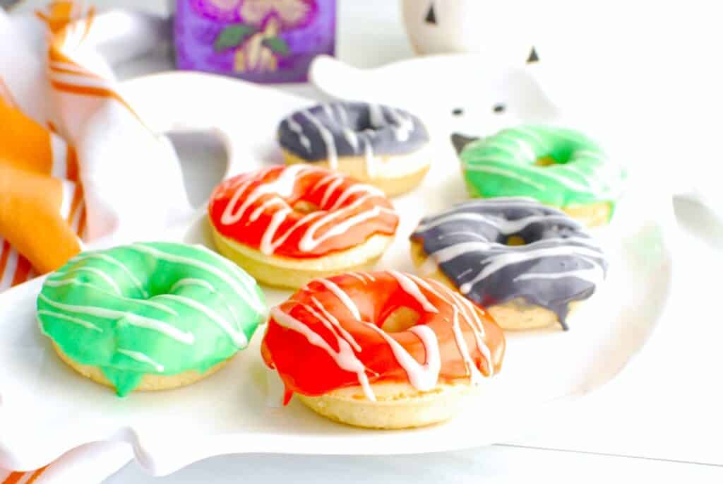 A platter with assorted color Halloween donuts.