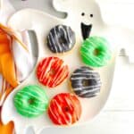 A ghost plate with different color Halloween donuts on it.