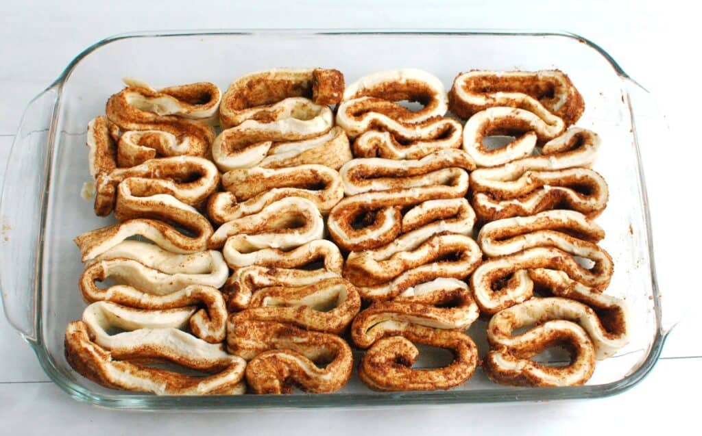 Cinnamon roll dough arranged in a baking dish.