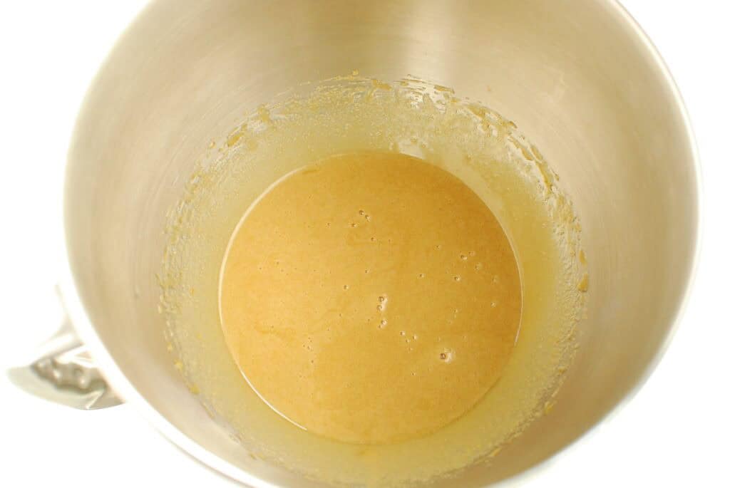 Olive oil, brown sugar, granulated sugar, egg, and vanilla extract mixed together in a silver bowl.