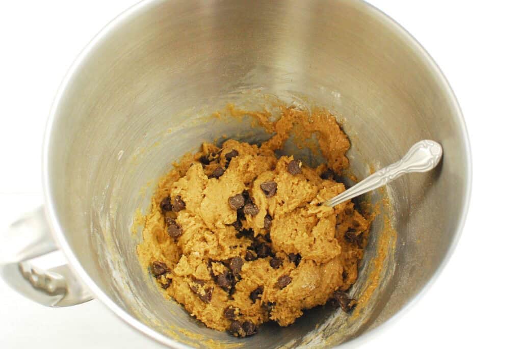Cookie dough in a silver mixing bowl.