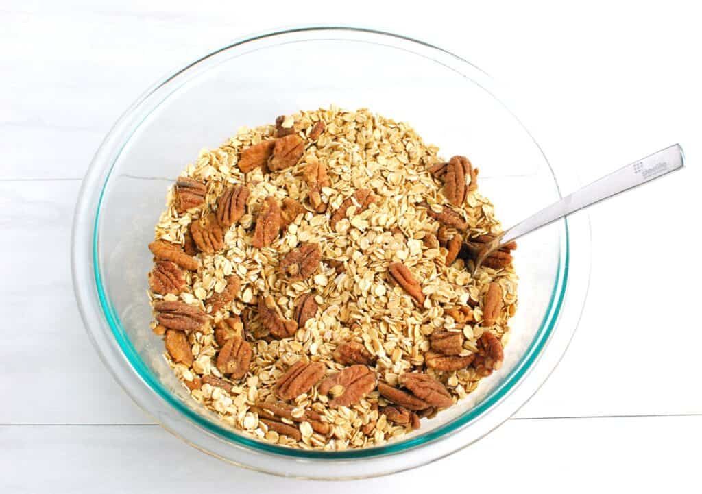 Oats, pecans, and seasonings mixed together in a glass bowl.