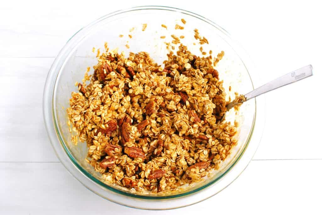 Granola ingredients mixed together in a glass bowl.