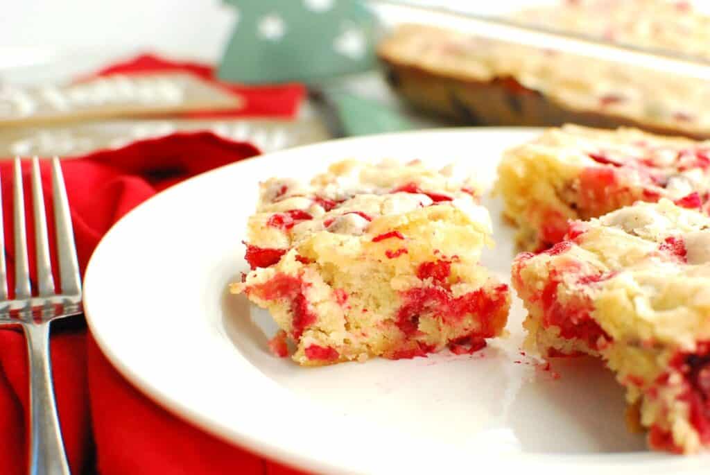 A close up of a slice of dairy-free cranberry Christmas cake on a white plate.