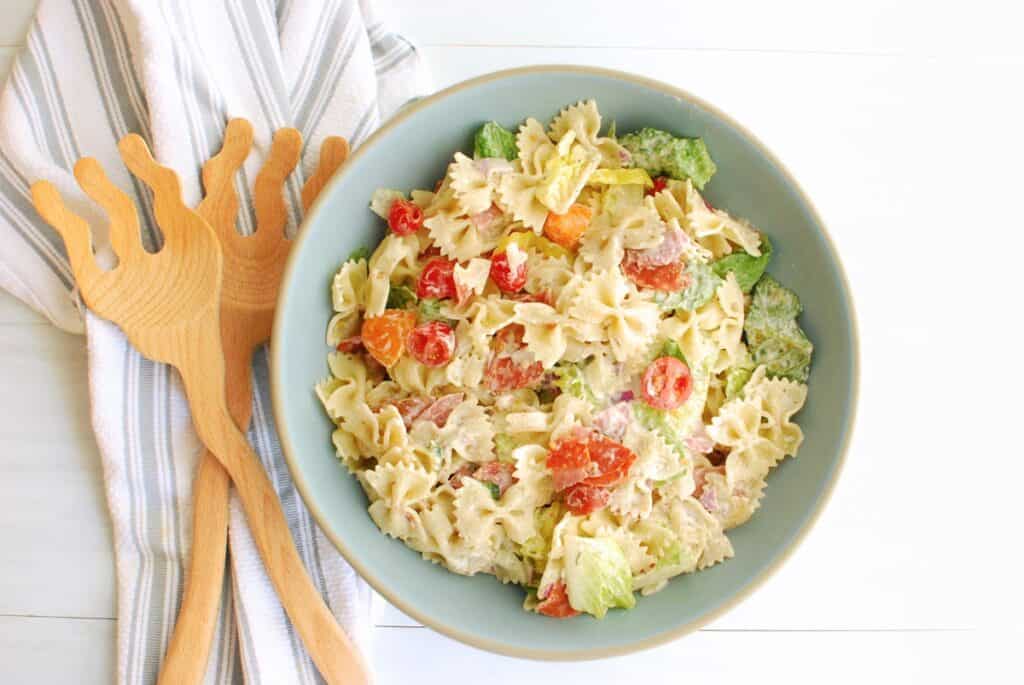 Dairy-free Italian grinder pasta salad in a bowl next to serving utensils and a napkin.