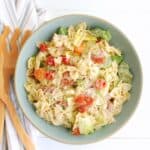 Overhead shot of a bowl of Italian grinder pasta salad next to a napkin and serving utensils.