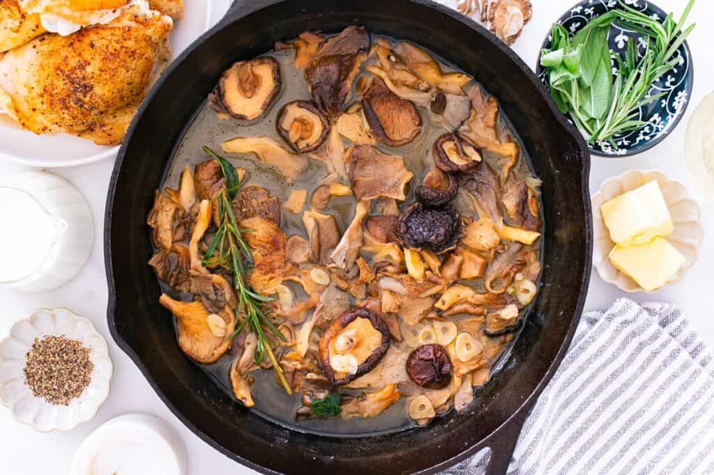 Mushrooms, garlic, wine, rosemary, and sage in a skillet.