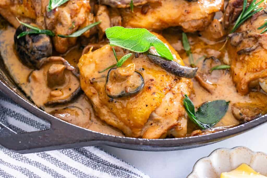 A close up of a chicken thigh with a creamy mushroom sauce.