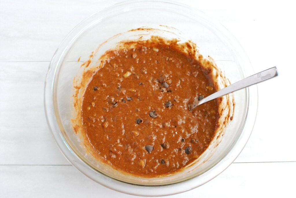 All the banana bread ingredients stirred together in a glass mixing bowl.