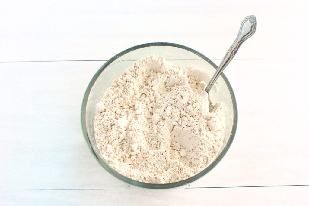 Flour, cinnamon, baking powder, baking soda, and salt combined in a glass bowl.