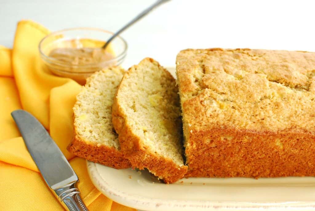 A loaf of plantain bread on a plate with two slices cut.