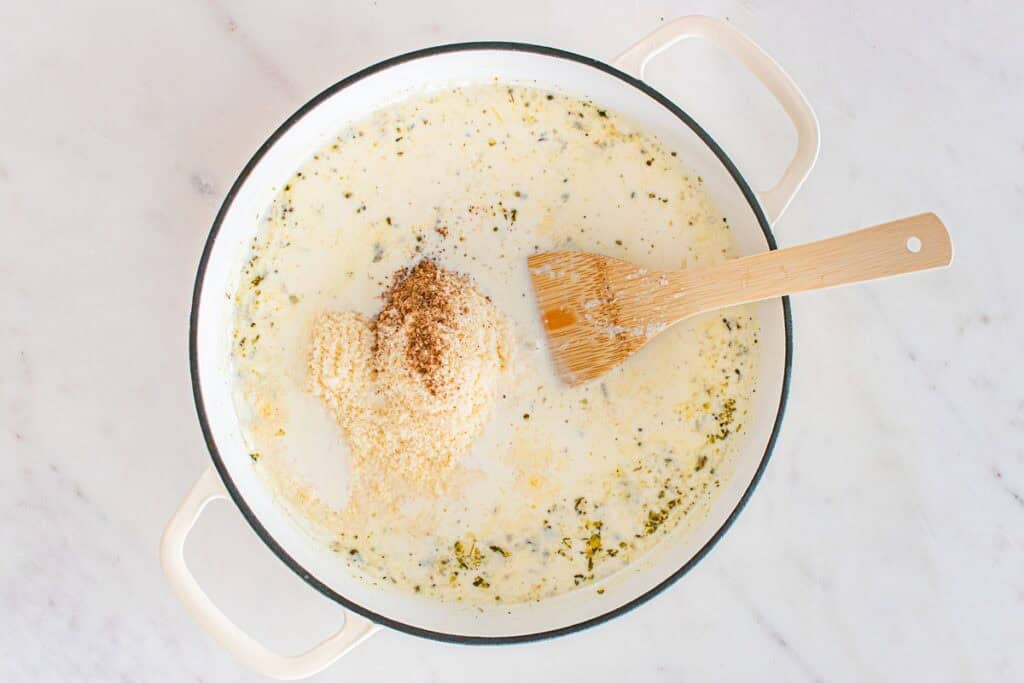 Oat milk, broth, dairy free parmesan, and nutmeg added to the skillet.