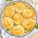 A skillet with dairy free chicken broccoli pot pie with biscuits as the topping, garnished with dairy-free parmesan and basil.