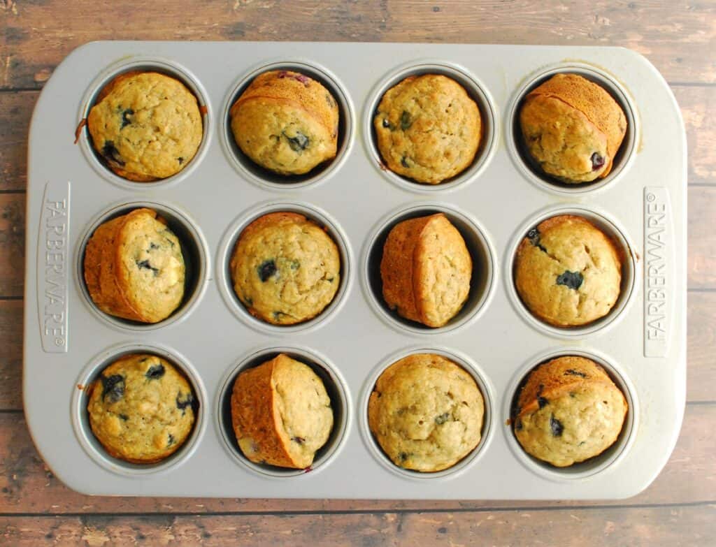 A muffin tin with just-baked banana blueberry muffins.