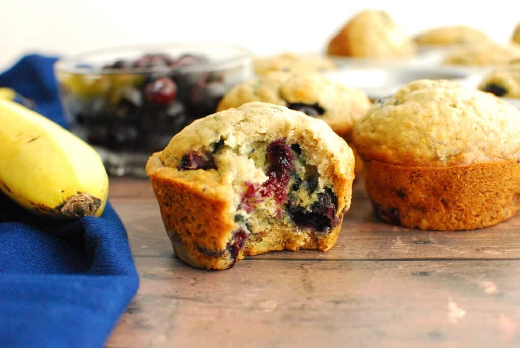 A dairy free blueberry banana muffin with a bite taken out of it.