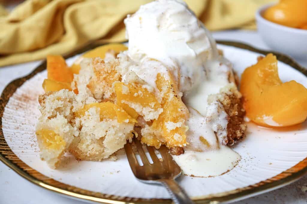 Dairy free peach cobbler topped with dairy-free ice cream.