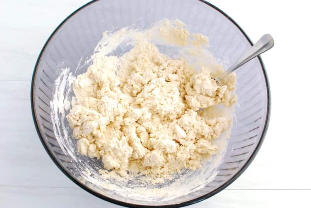 Biscuit dough in a glass mixing bowl.