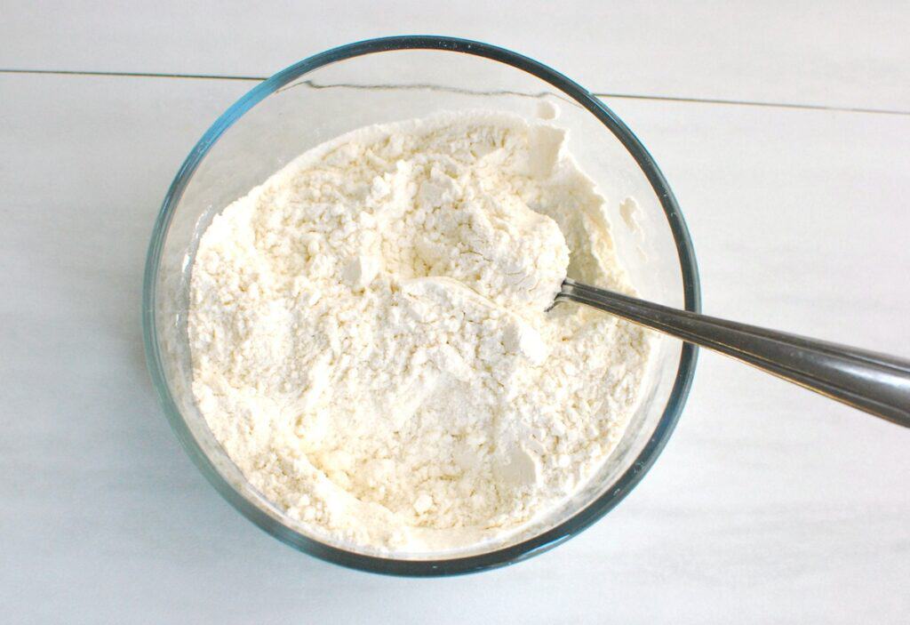 Flour, baking soda, and salt stirred together in a glass bowl.