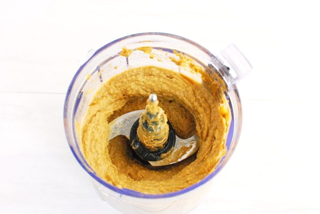 Chickpeas, sunflower butter, maple syrup, and vanilla mixed together in a small food processor bowl.