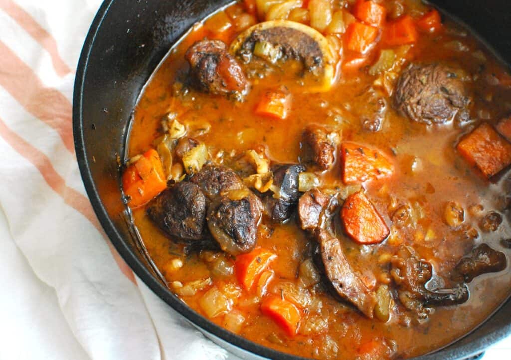 A pot with braised beef shanks cooked with carrots and white beans.