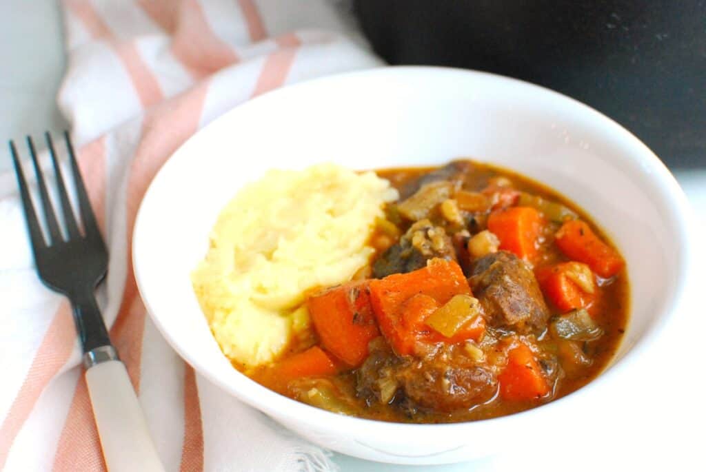 Braised beef shanks served over mashed potatoes in a bowl.