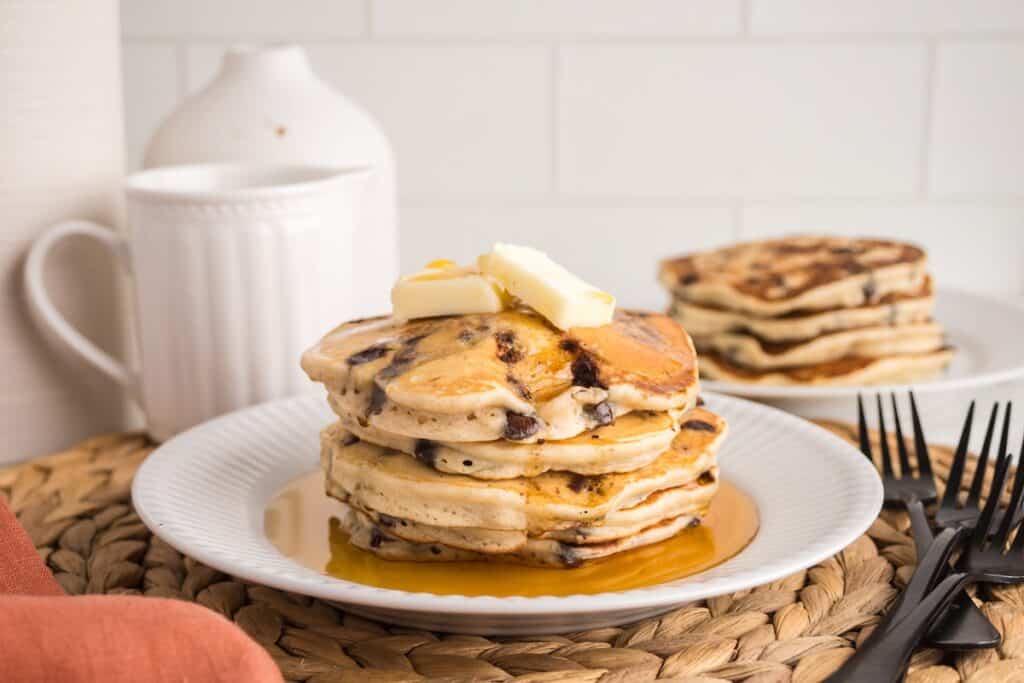 A stack of dairy free chocolate chip pancakes topped with dairy-free butter and syrup.