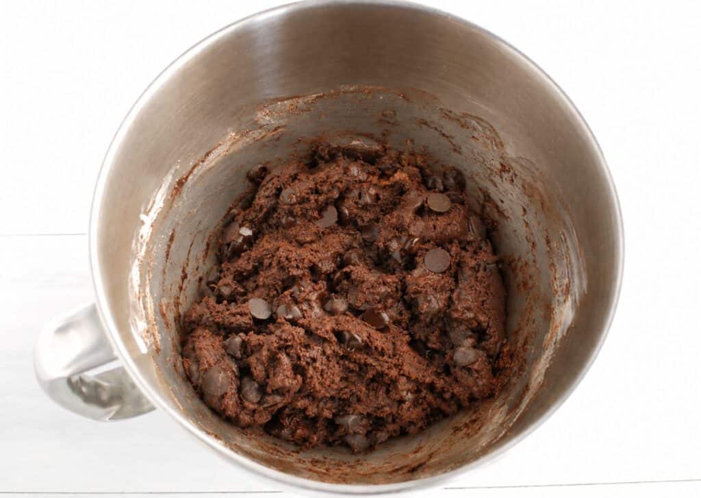 Cookie dough in a silver mixing bowl.