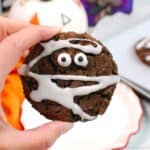 A hand holding a chocolate mummy cookie.