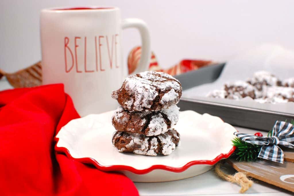 A stack of three chocolate crinkle cookies made with oil on a plate.