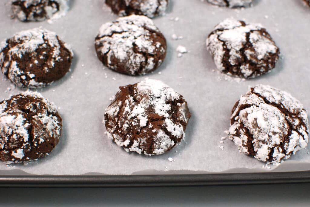 A baking sheet with just-baked chocolate crinkle cookies.