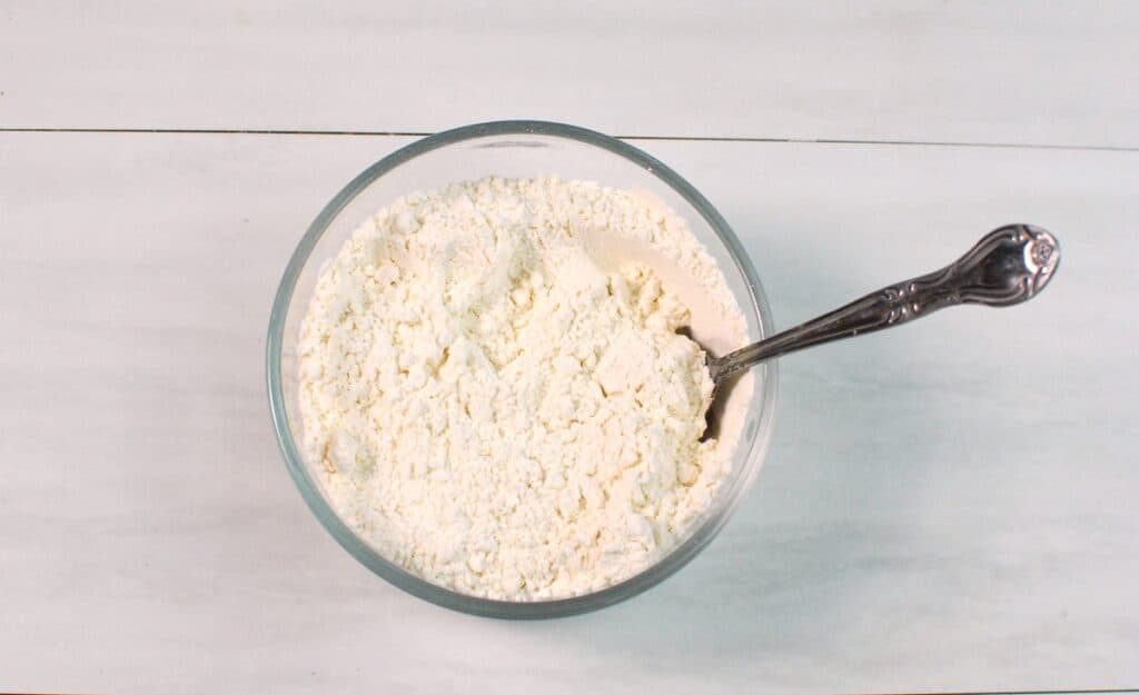 Flour, baking powder, and salt mixed together in a glass bowl.