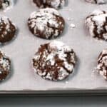 Chocolate crinkle cookies on a parchment lined baking sheet.