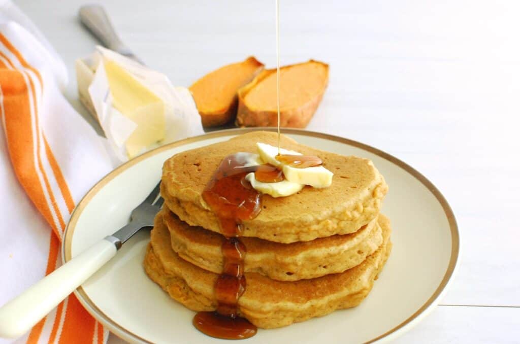 Dairy free gluten free sweet potato pancakes being drizzled with maple syrup.