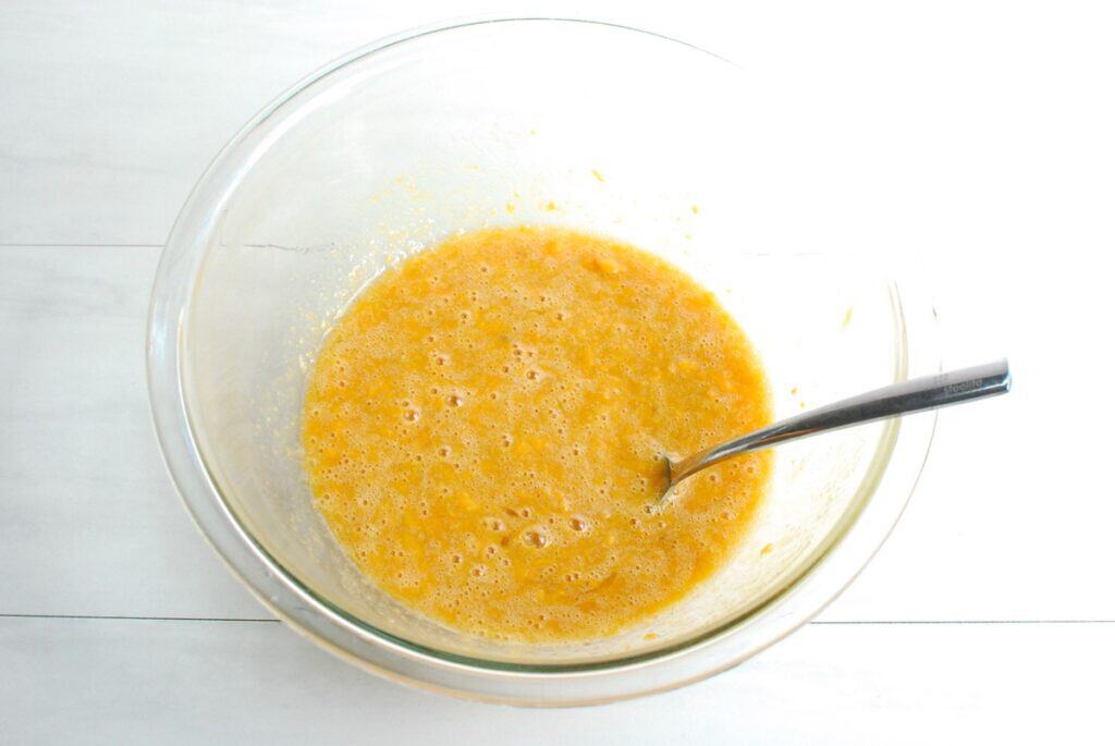 Sweet potato, eggs, brown sugar, and oil mixed together in a glass bowl.