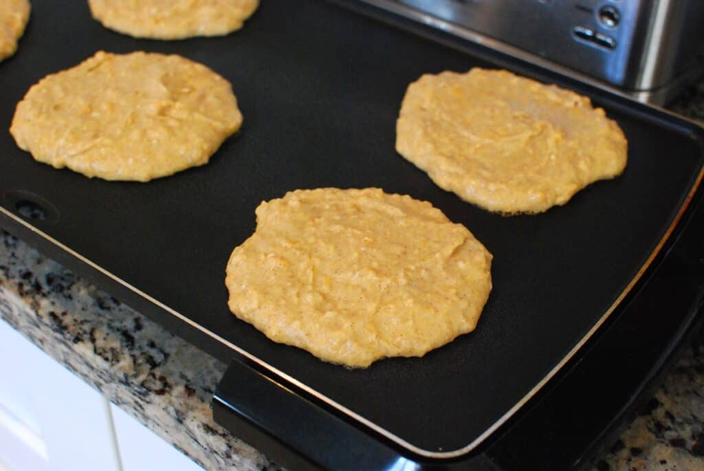 Pancakes cooking on a griddle.