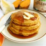 A stack of three gluten free sweet potato pancakes topped with dairy free butter and syrup.