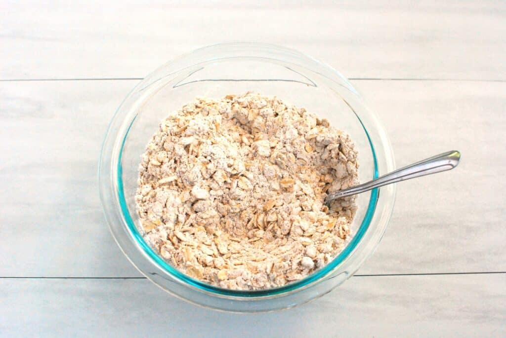 Flour, cinnamon, pumpkin spice, baking powder, baking soda, and salt mixed together in a glass bowl.