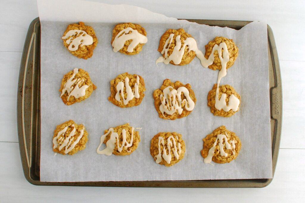 A baking sheet with vegan iced pumpkin oatmeal cookies.