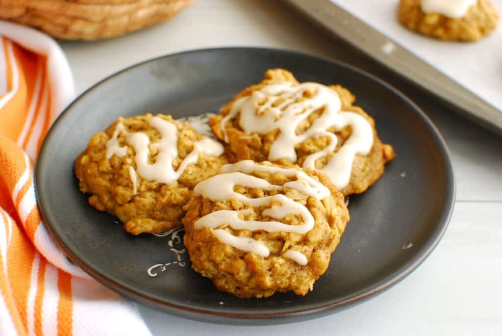 Three iced egg free dairy free pumpkin oatmeal cookies on a plate.