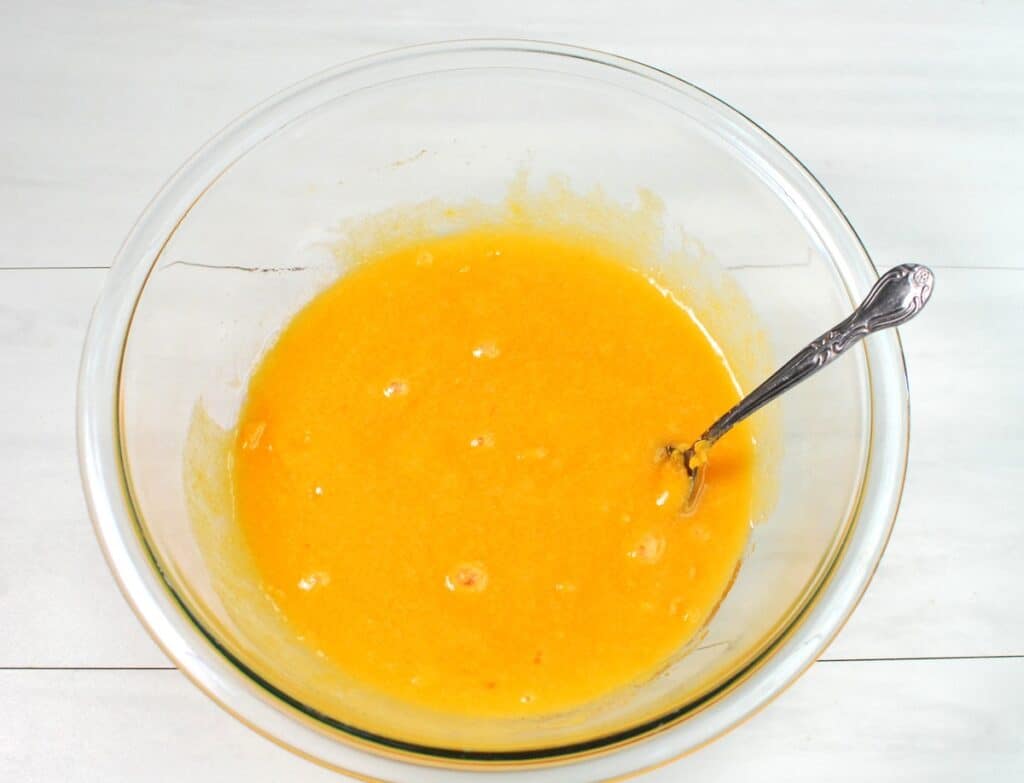 Sweet potato, sugar, egg, oil, and vanilla mixed together in a glass bowl.