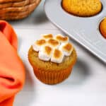 A sweet potato cupcakes topped with toasted marshmallows on a white table.
